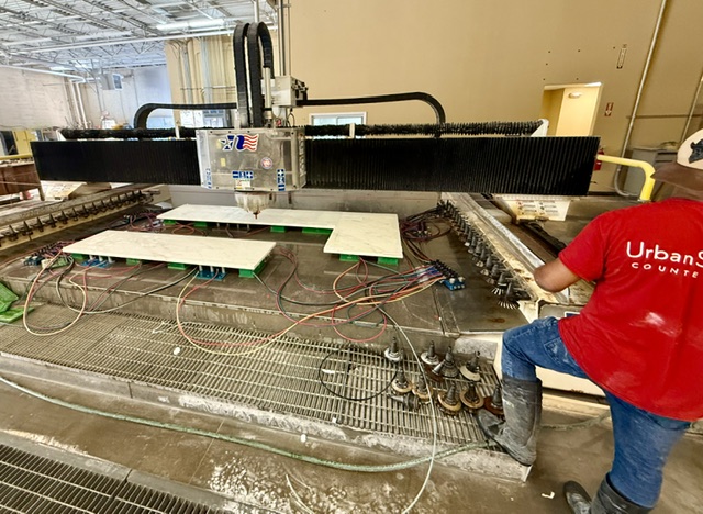 UrbanSource technician beside countertop pieces on the CNC cutting bed