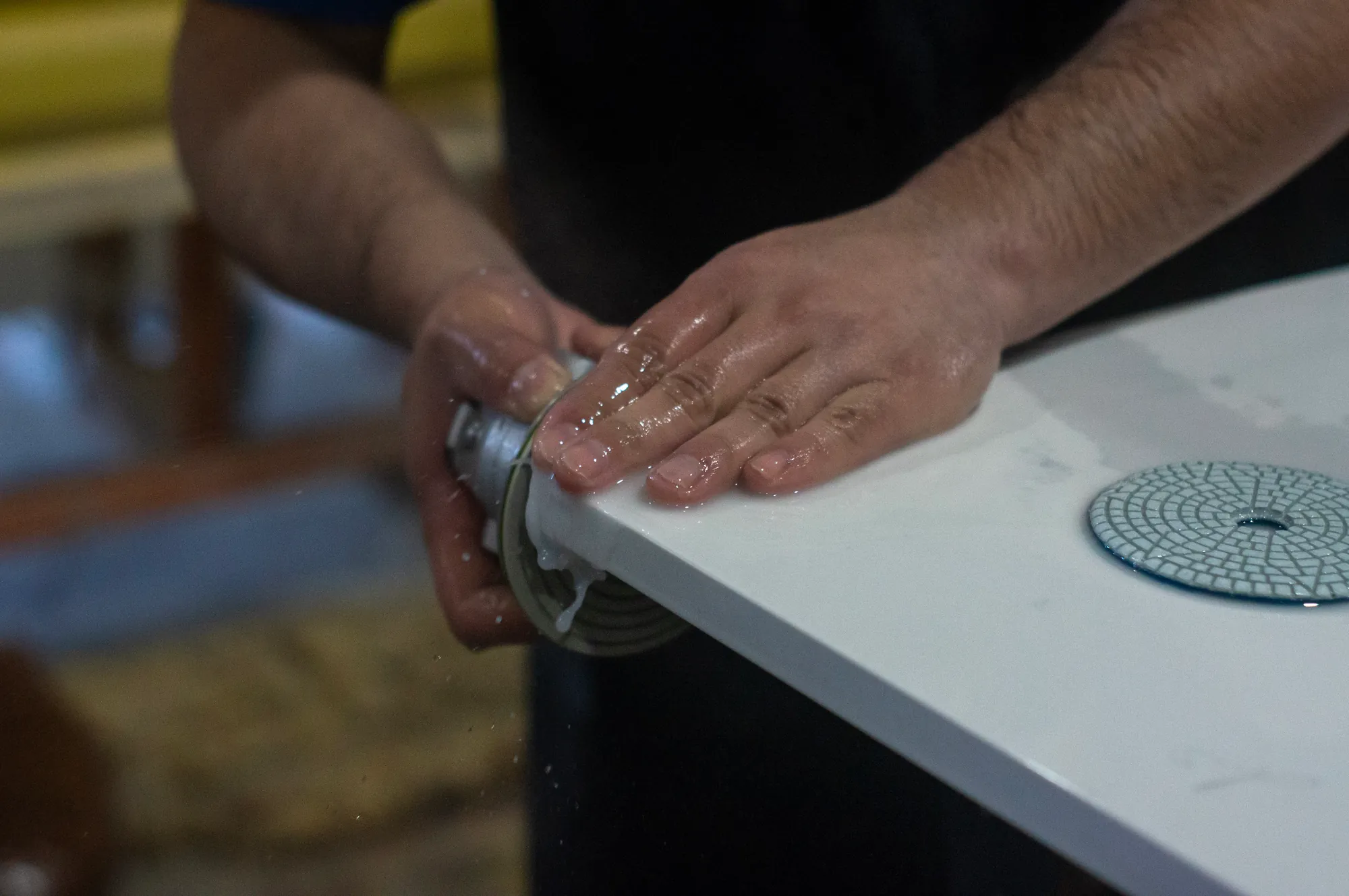 UrbanSource fabricator hand-polishing the edge of a white countertop