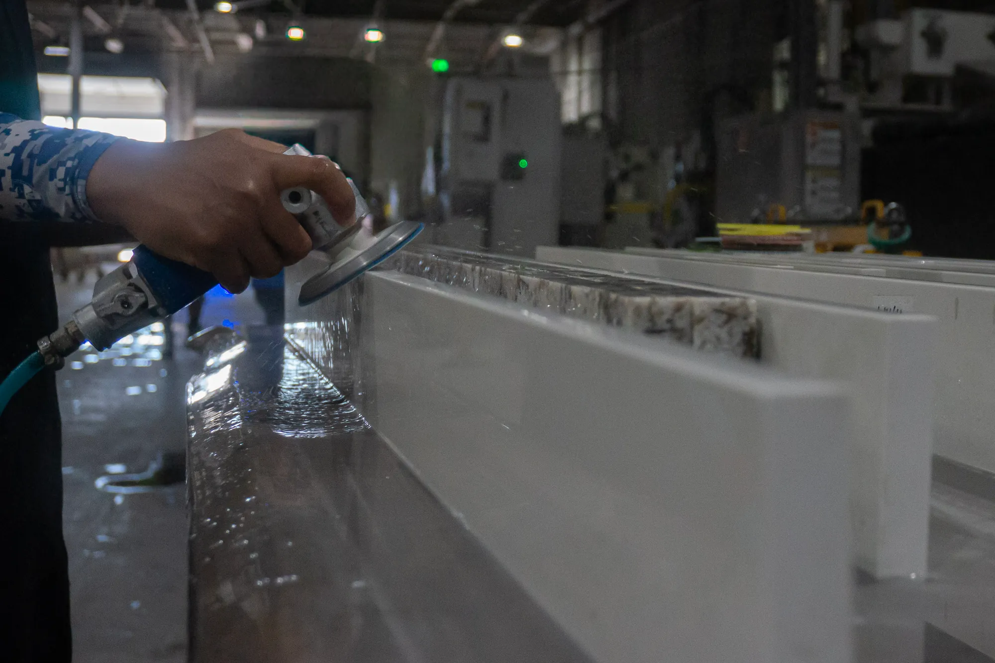 UrbanSource fabricator wet-finishing and inspecting a white countertop edge